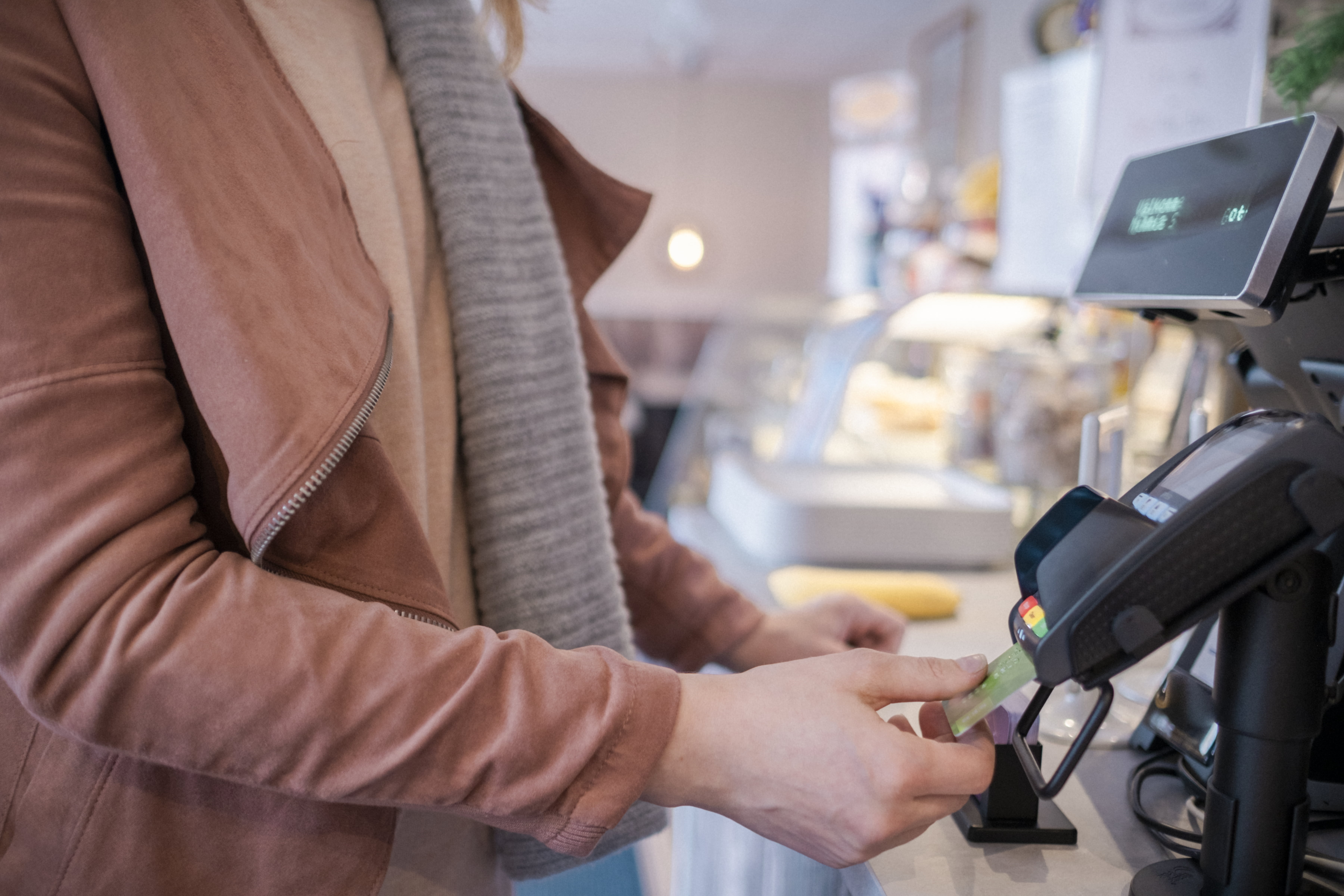 Nærbilde av en hånd som betaler med kort i butikk