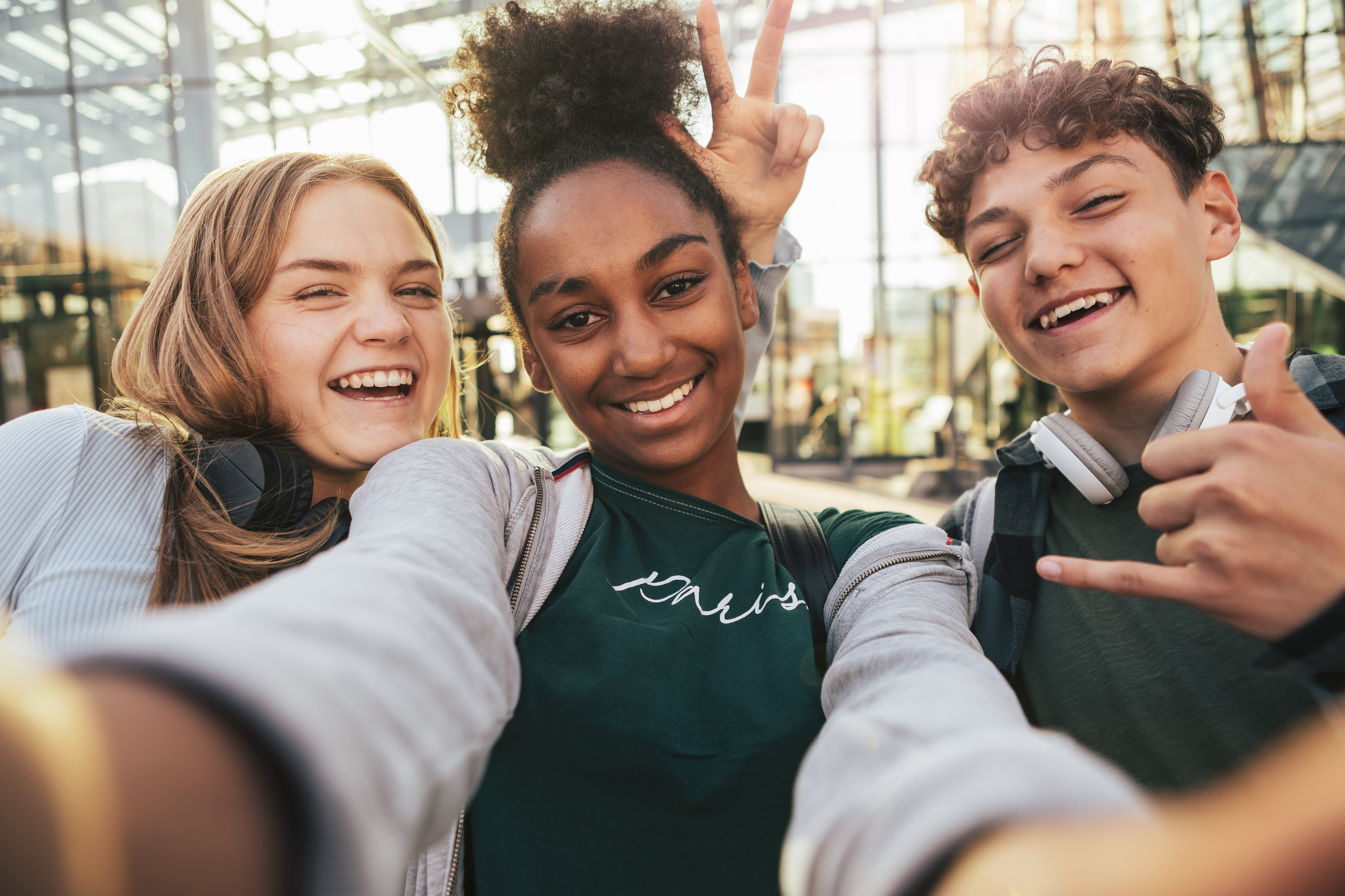 Tre glade ungdommer som smiler til kamera