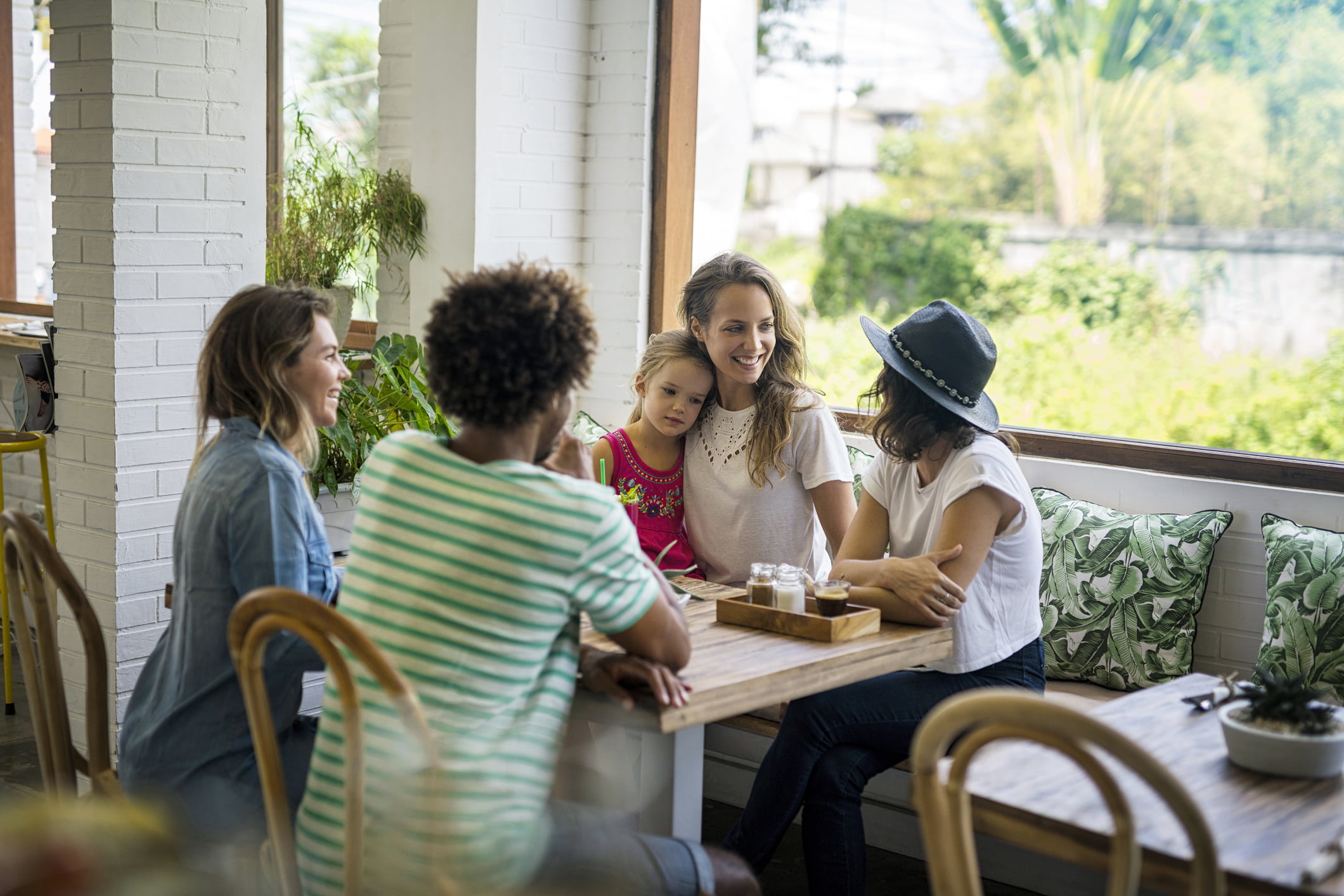 Smilende kvinner på kafe, snakker sammen.