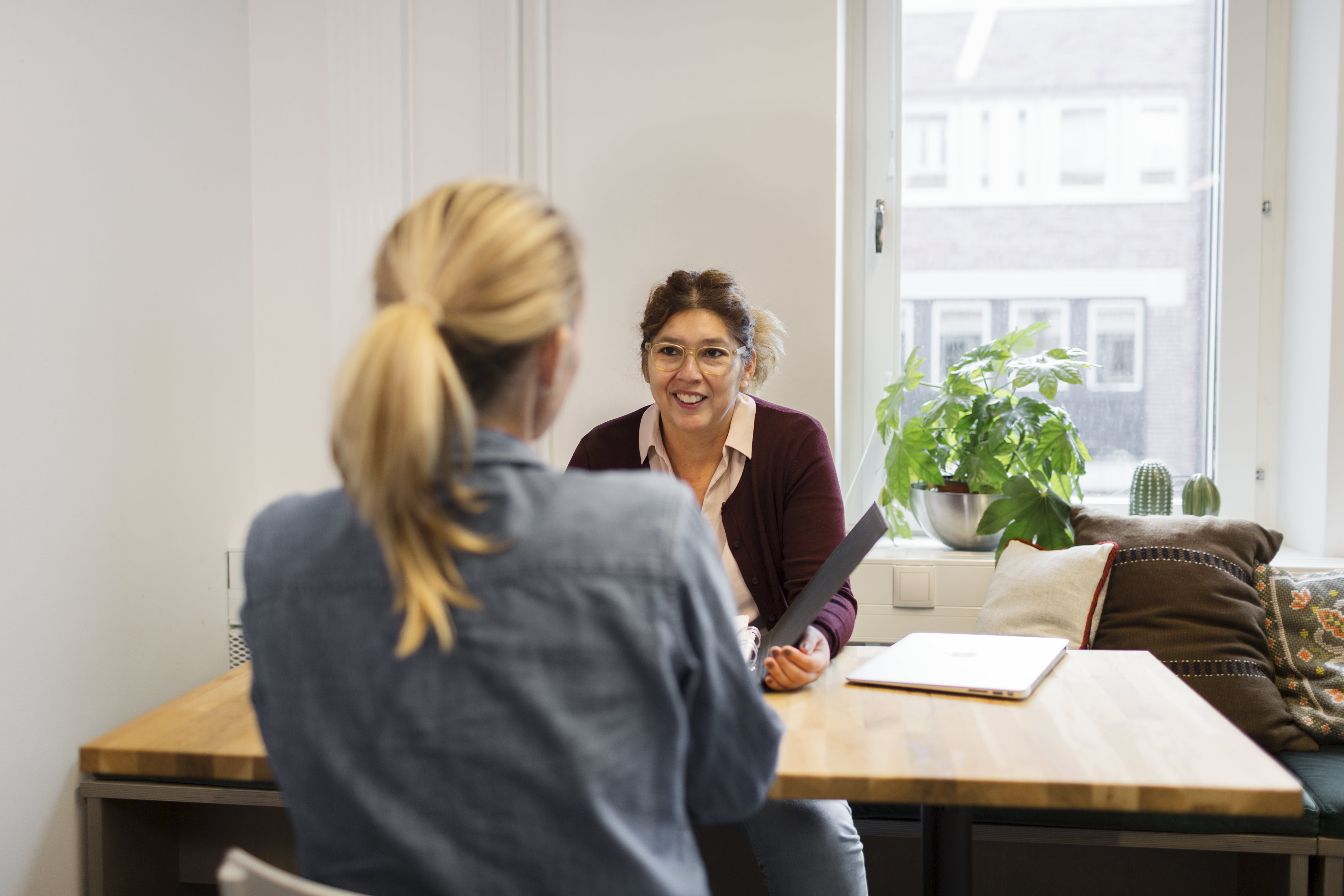 To damer som sitter med papirer over et bord