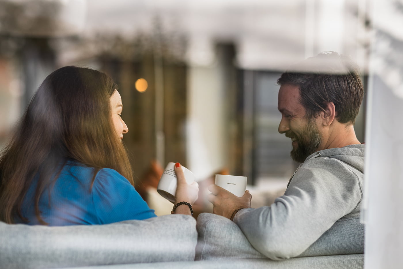 Ser inn mot kvinne og mann som sitter i sofaen med en kaffekopp hver
