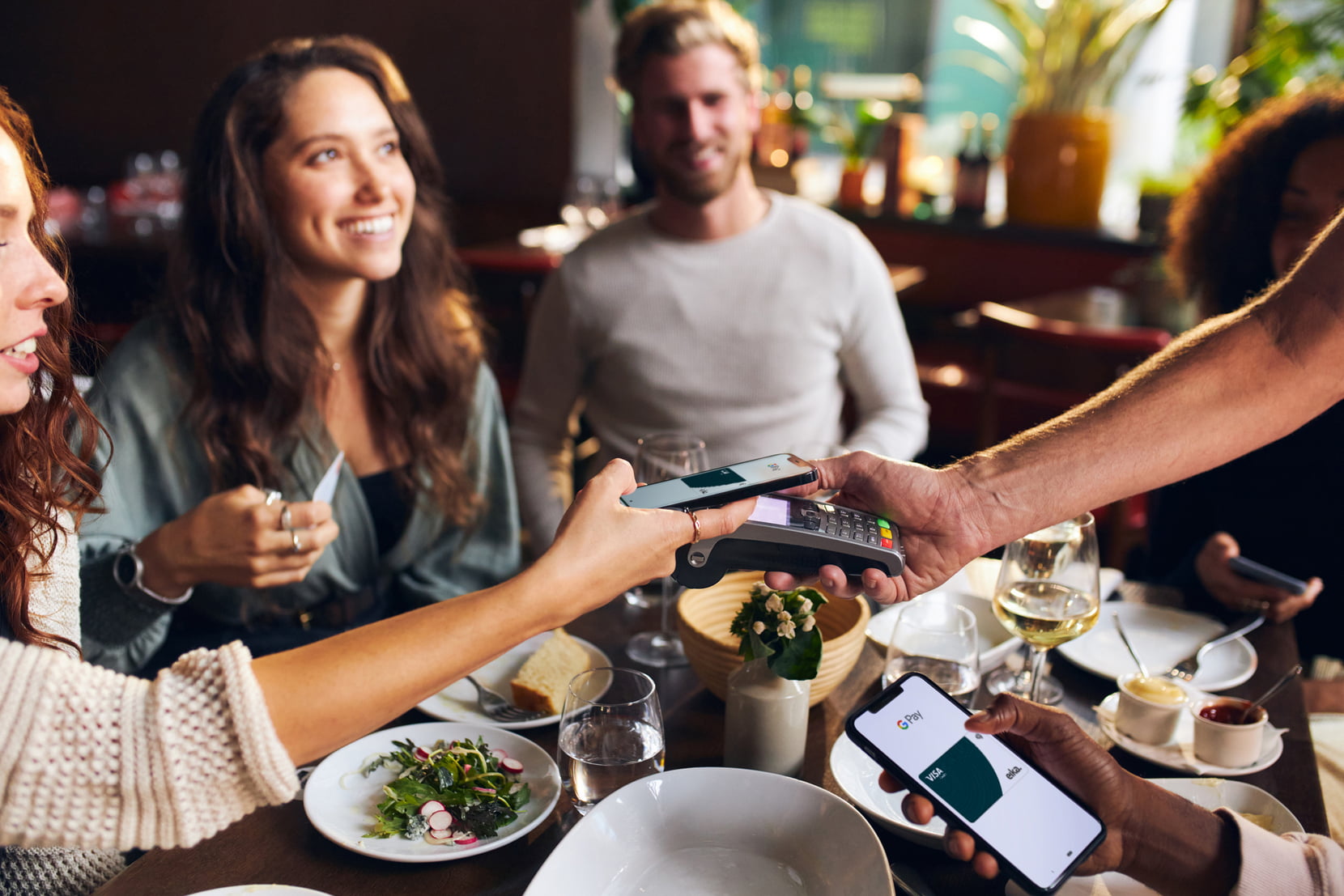 Bilde av dame som betaler med mobilen for middag på restaurant. 