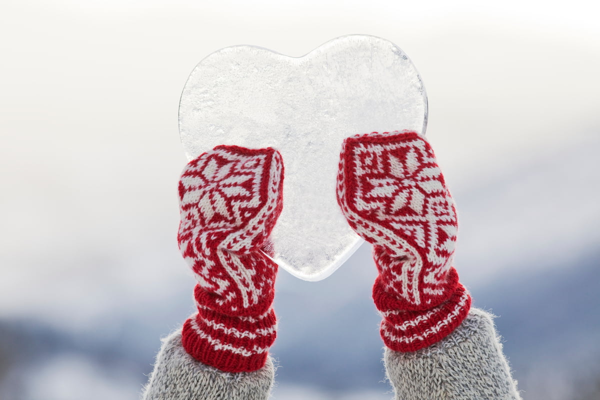 Bilde av to hender med røde votter som holder et ishjerte. 