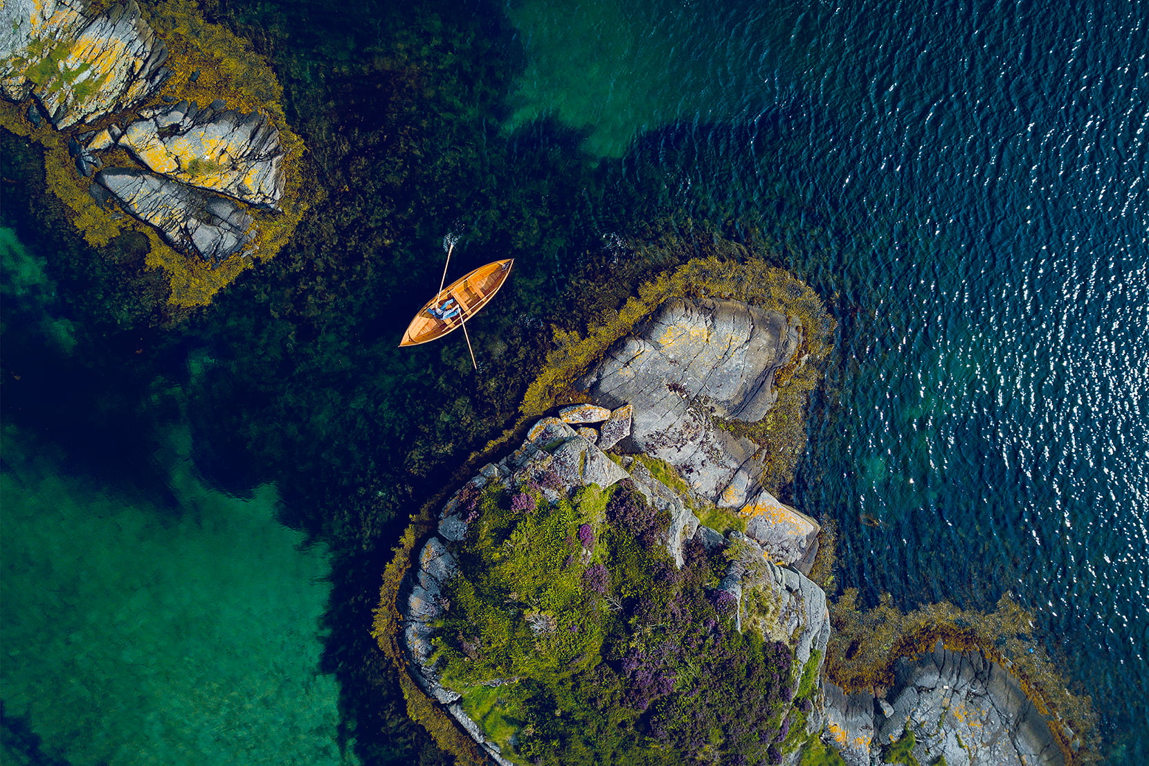 Dronebilde av mann i trebåt utenfor Åkrehamn på Karmøy