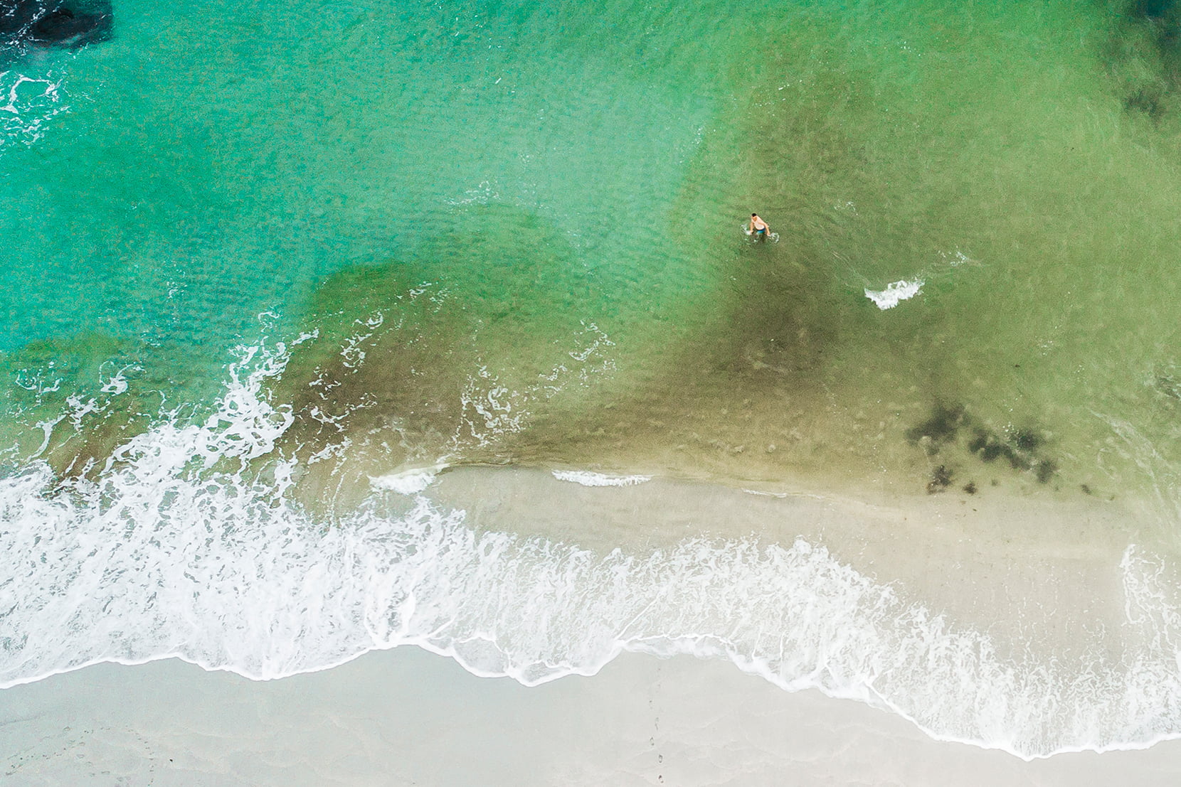 Dronebilde av mann som bader på Sandvesanden på Karmøy