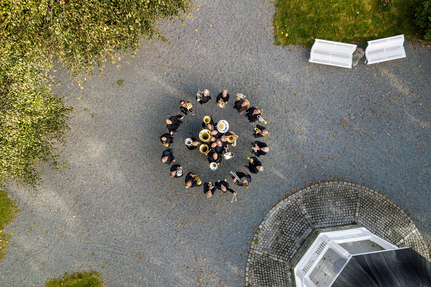 Dronebilde av korps som står i en ring i parken i Kopervik