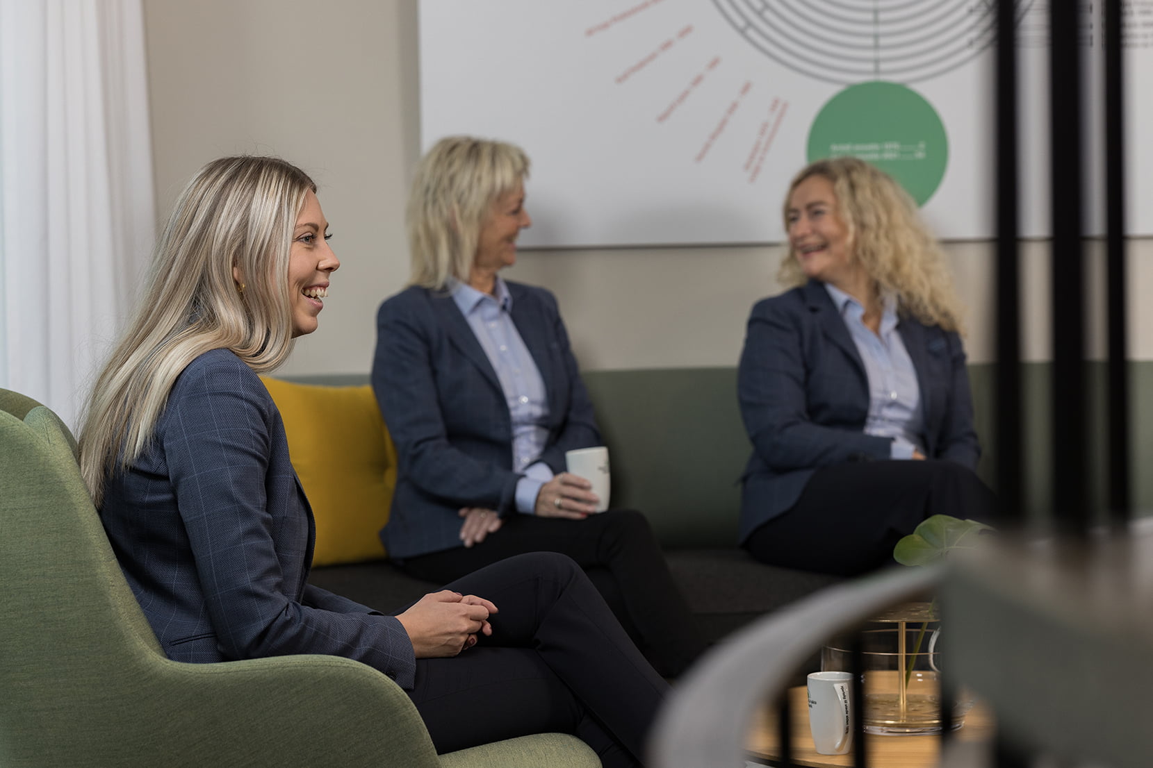 Smilende ansatte samlet for kaffeprat med Birgitte i fokus. 