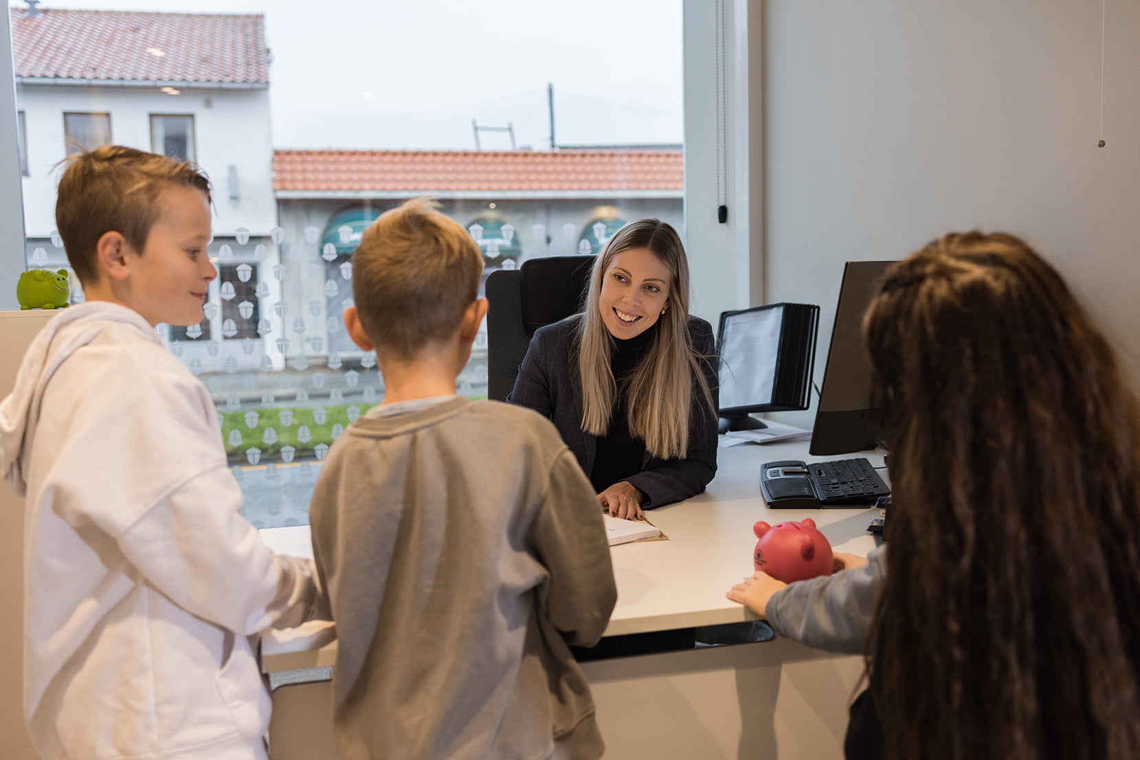 Tre barn sammen med mor på kontoret til rådgiver for å snakke om sparing