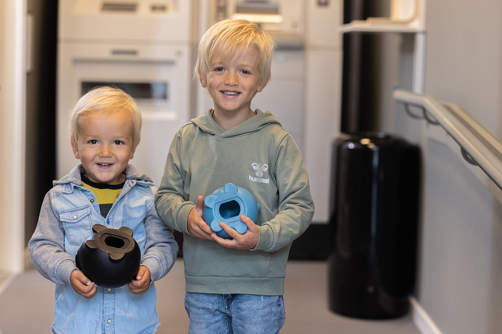 To smilende gutter som akkurat har tømt sparegrisen i innskuddsmaskinen på kontoret i Skudeneshavn