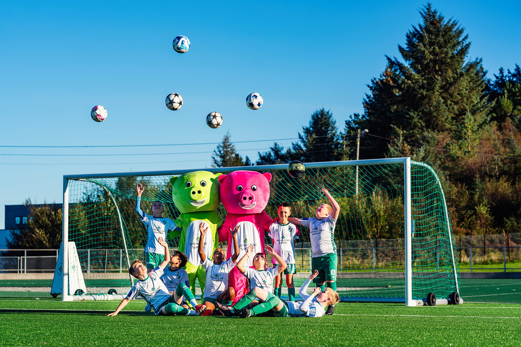 Bilde av Glagrisene og et lag fra Kopervik IL som kaster fotballer i lufta på fotballbanen