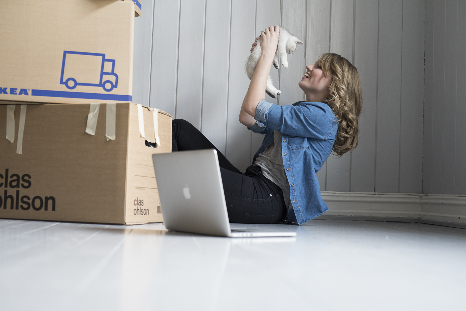 Dame holder katt  med flytte esker på gulvet. foto